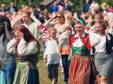 Sunnansj?, Sweden - June 20, 2015: Men, women and children, some in traditional folk customes, dancing around a maypole at a traditional swedish midsummer celebration. The song and dance performed here is the traditional Sm? grodorna, or The Little Frogs in english.